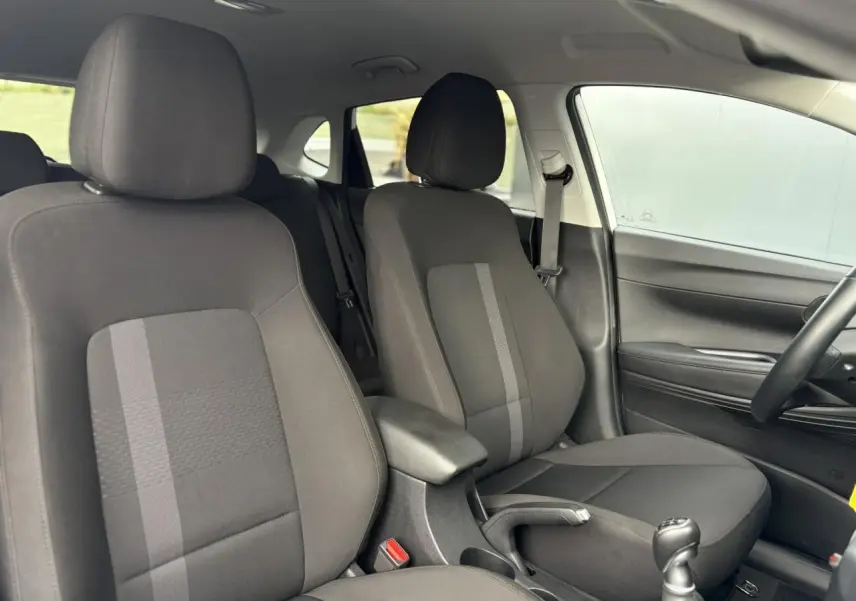 Vue intérieure côté droit des sièges avant noirs avec accoudoir central et levier de vitesses manuel d'une Hyundai i20 2025.