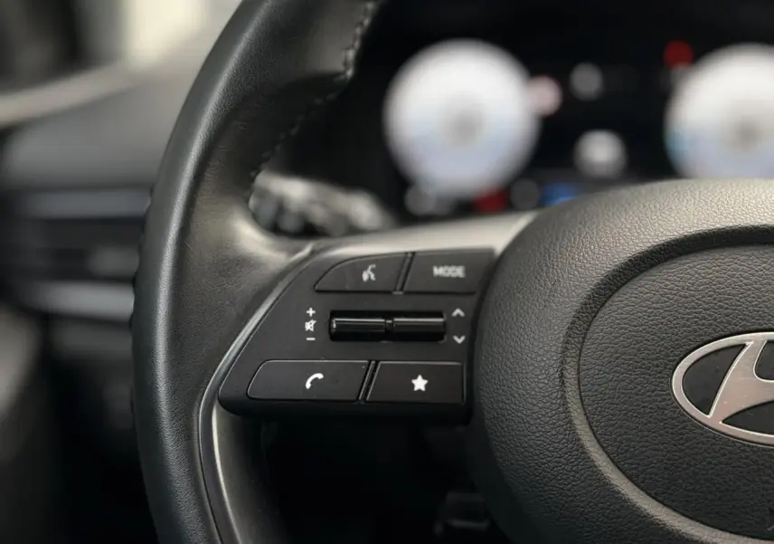 Gros plan sur le volant cuir de la Hyundai i20 2025 avec commandes multimédia intégrées côté gauche.