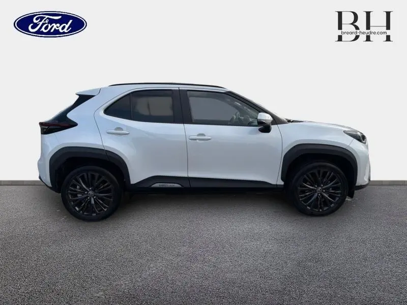 Vue de profil droit du Toyota Yaris Cross blanc lunaire nacré avec jantes noires et détails noirs contrastants.