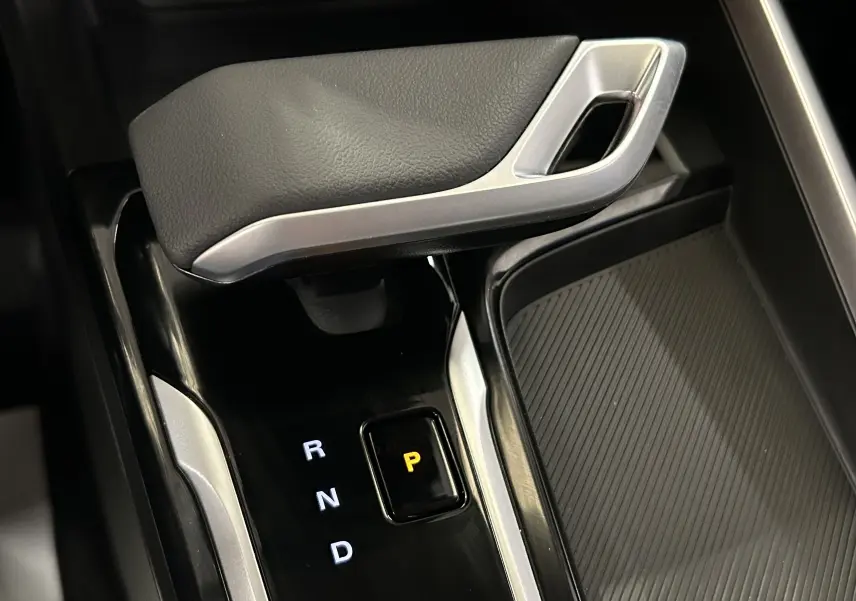 Gros plan sur la commande de boîte automatique noire avec levier et indicateur de position P éclairé dans un MG ZS Hybrid+ gris.