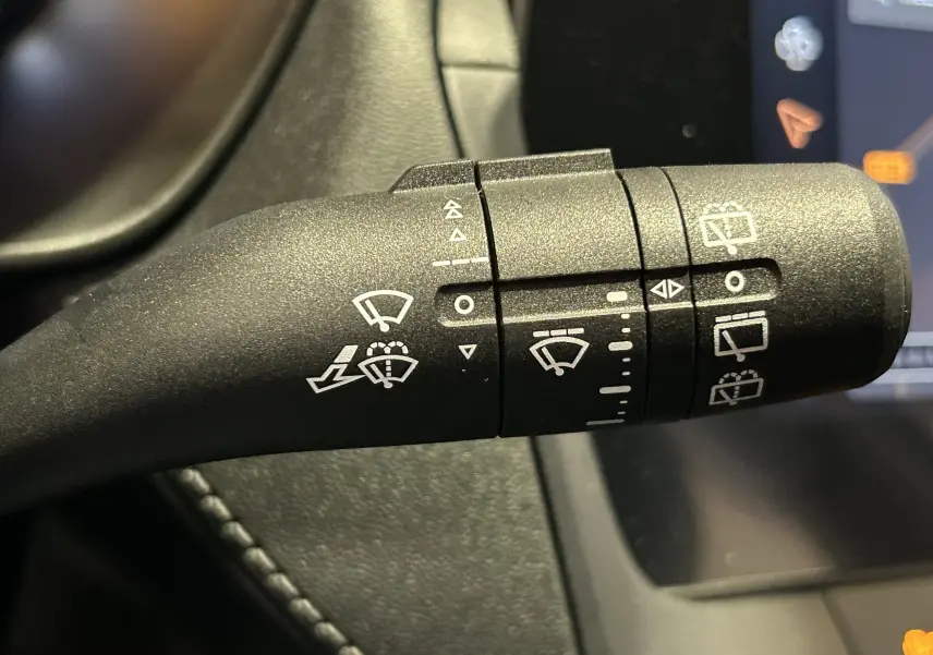 Gros plan sur la manette de commande des essuie-glaces du MG ZS Hybrid+ 2025, avec pictogrammes blancs sur fond noir.