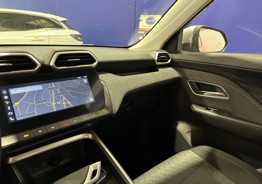 Vue intérieure côté passager du MG ZS Hybrid+ 2025 avec tableau de bord noir, écran GPS tactile et sellerie tissu gris.