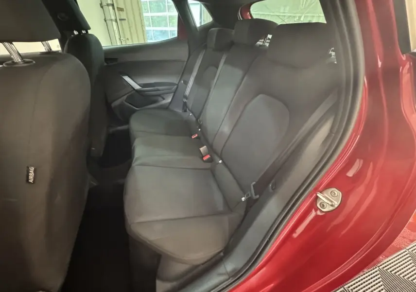 Vue intérieure côté droit sur la banquette arrière noire d’une SEAT Ibiza rouge 2024 avec portière ouverte.
