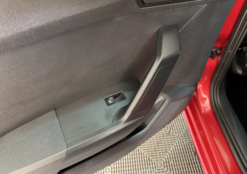 Gros plan sur la porte avant gauche rouge d’une SEAT Ibiza 2024, avec commande de verrouillage centralisé visible.