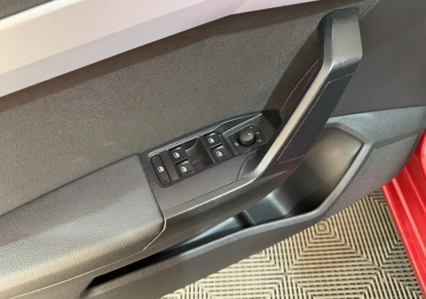 Gros plan sur la porte côté conducteur rouge de la SEAT IBIZA 2024, montrant les commandes électriques des vitres et rétroviseurs.