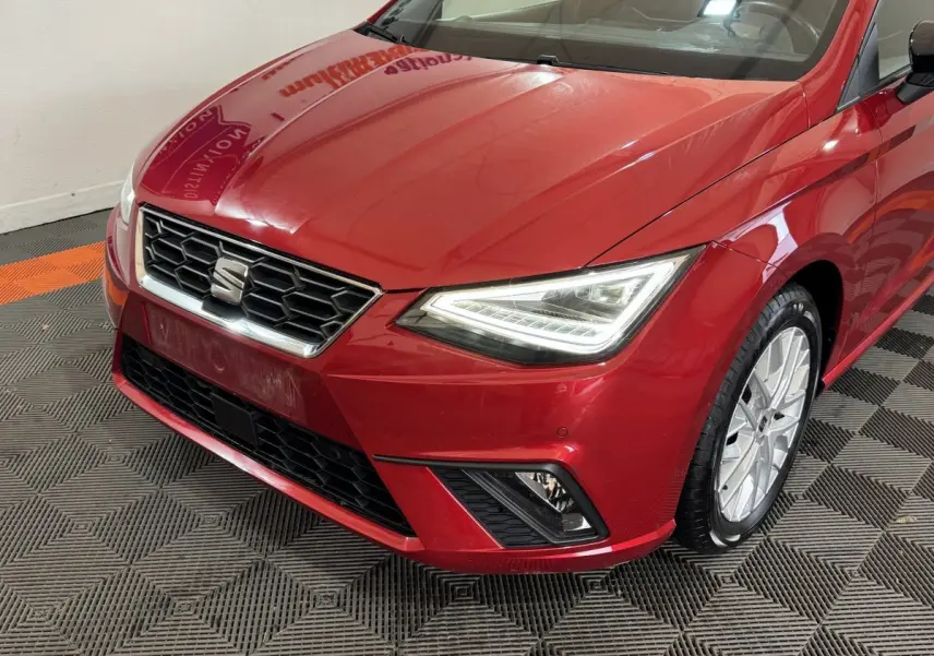 Vue 3/4 avant droit d'une SEAT Ibiza 1.0 TSI 110 FR rouge avec phares LED et jantes alliage visibles.