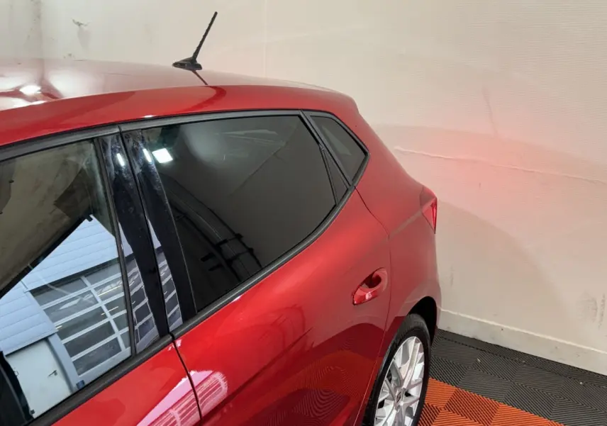 Vue 3/4 arrière droite d'une SEAT Ibiza 2024 rouge avec vitres teintées et jantes alliage argentées.