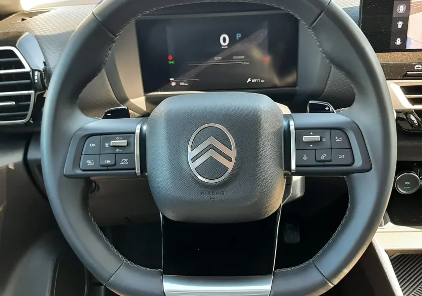 Vue frontale du volant noir de la Citroën C4 1.2 Hybrid 2025 avec commandes intégrées et tableau de bord digital.