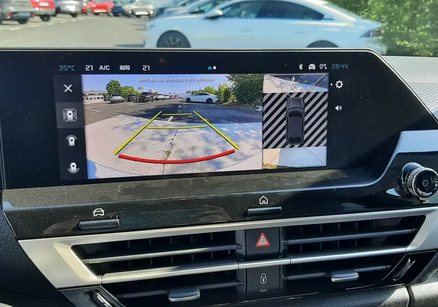 Écran intérieur montrant la caméra de recul avec vue arrière d’une Citroën C4 blanche garée en extérieur.