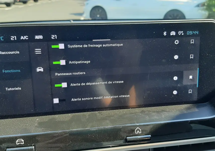 Vue intérieure du tableau de bord de la Citroën C4 blanche, avec l'écran tactile affichant les options d'aide à la conduite.