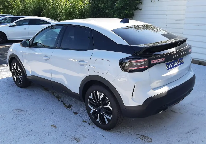Vue 3/4 arrière droite d'une Citroën C4 blanche Okenite avec toit noir et jantes bi-ton, stationnée en extérieur.