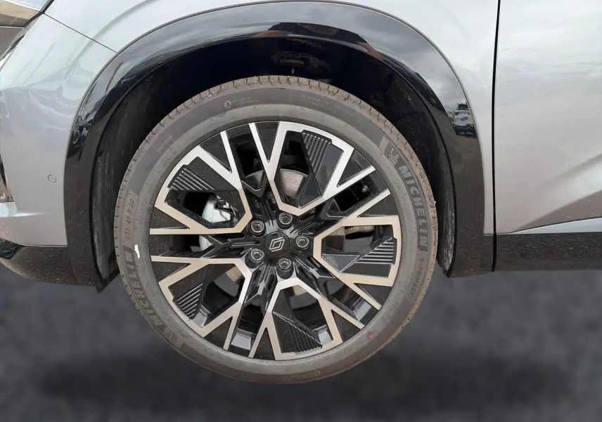 Gros plan sur la roue avant gauche du Renault Austral gris schiste avec jante alliage noire et argentée au design géométrique.