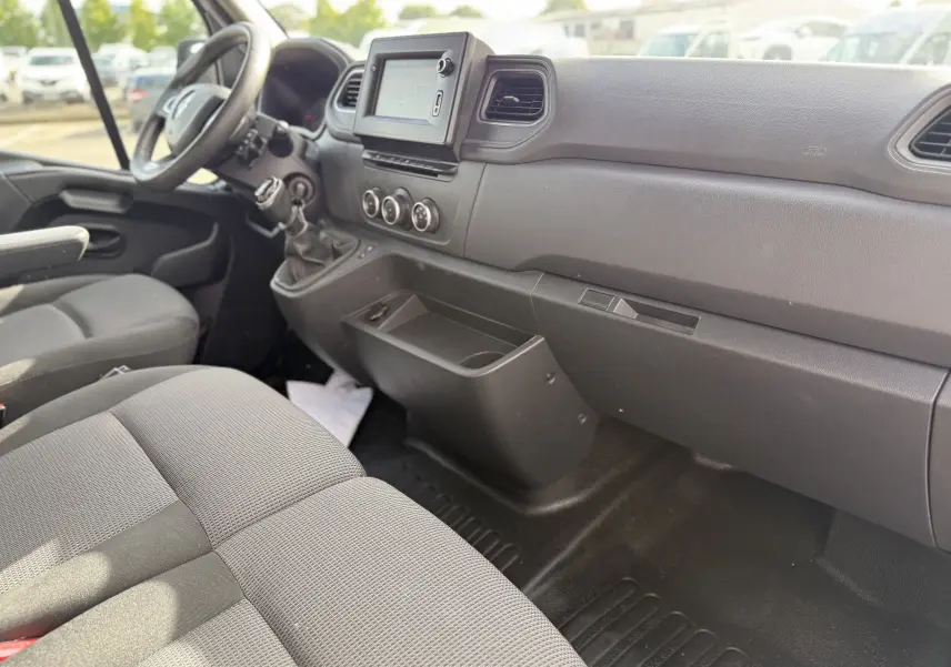 Intérieur du Renault Master 2020 vu côté passager, montrant tableau de bord noir et sièges tissu gris.