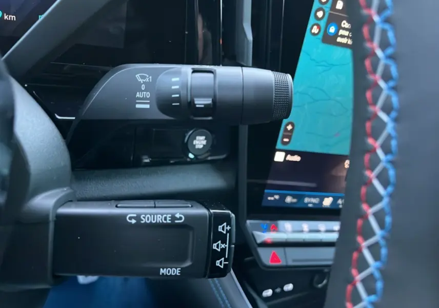 Gros plan sur les commandes au volant avec surpiqûres tricolores du Renault Rafale 4x4 300 blanc nacré toit noir.