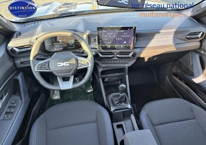 Vue intérieure frontale du tableau de bord et volant du Dacia Duster gris schiste, avec écran tactile et boîte manuelle.