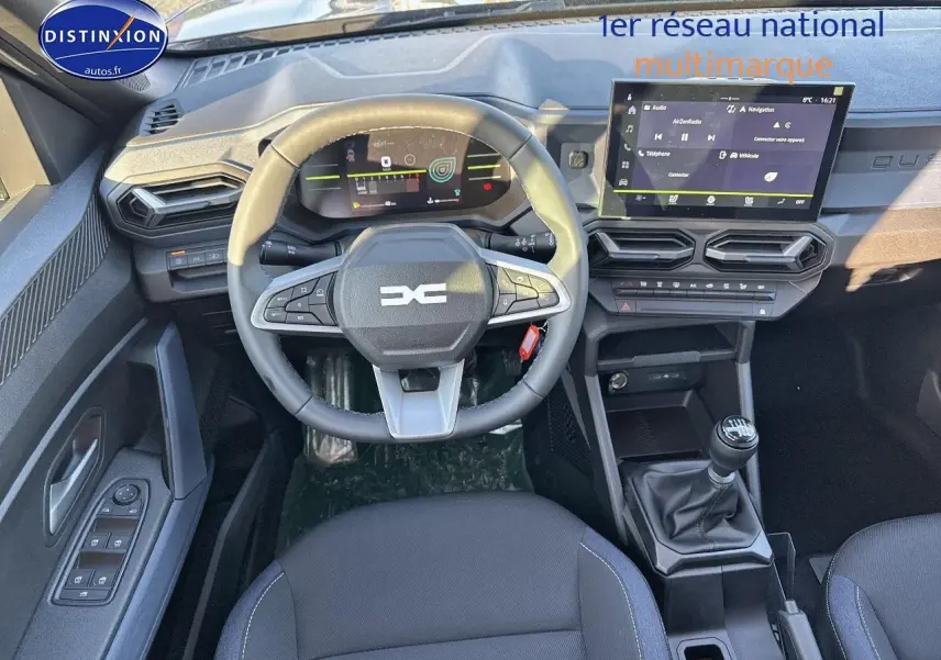 Vue intérieure avant du Dacia Duster 2025 gris schiste, volant multifonction et écran tactile central avec boîte manuelle.