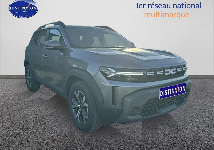 SUV Dacia Duster gris schiste en 3/4 avant droit avec jantes alu et barres de toit visibles.