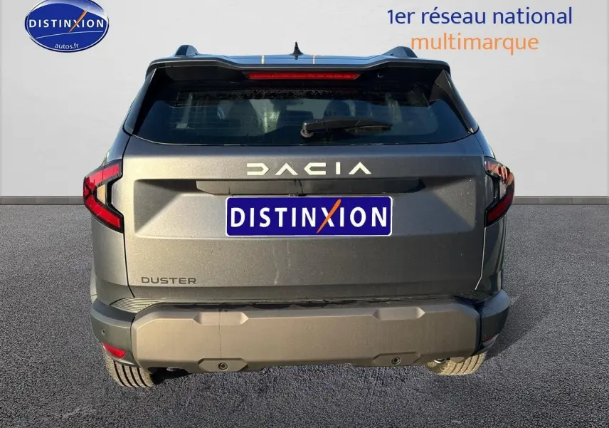 Vue arrière d'un Dacia Duster gris schiste 2025 avec feux LED et hayon noir mat, stationné sur sol goudronné.