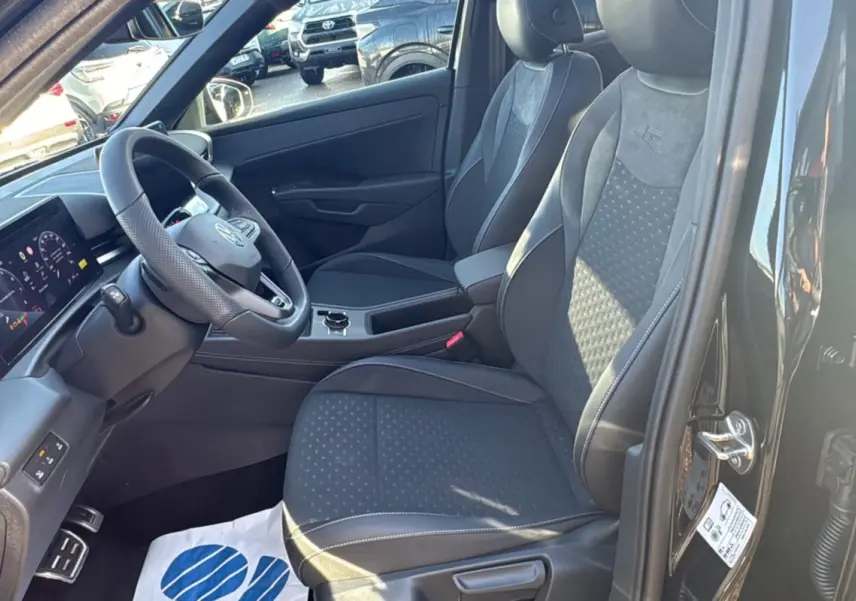 Vue intérieure côté conducteur du Volkswagen T-Roc noir ebène 2026, avec sièges tissu R-Line et volant cuir multifonctions.