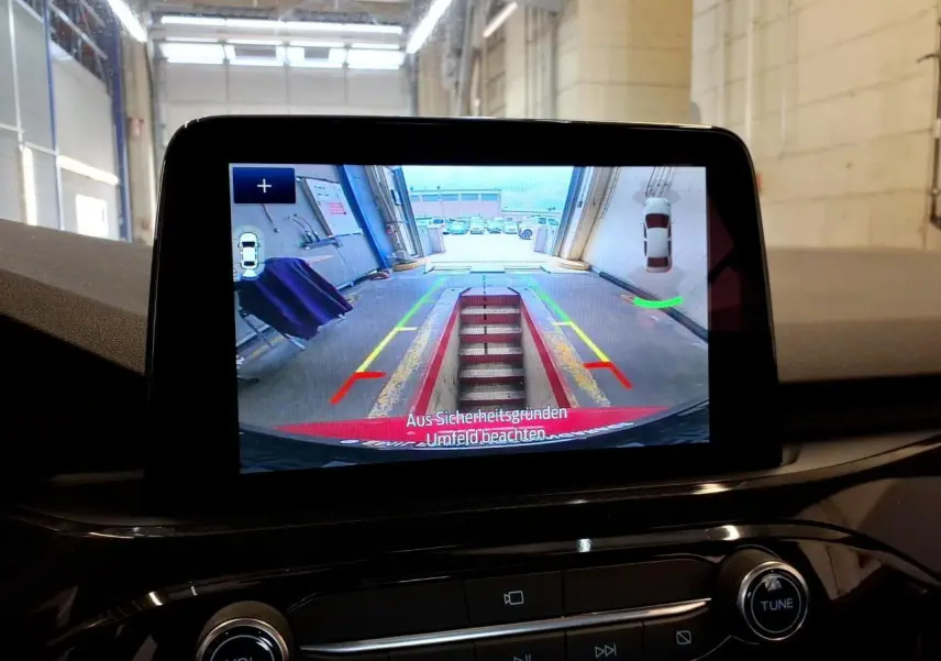 Écran tactile intérieur montrant la caméra de recul du Ford Kuga rouge, avec lignes de guidage colorées.