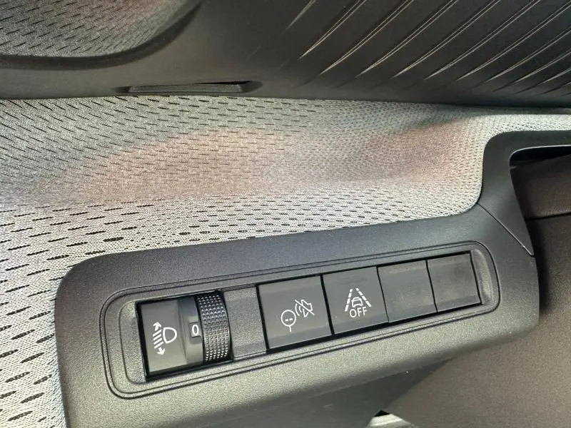 Détail intérieur montrant les commandes d'assistance et réglage des phares sur la Citroën C3 Aircross 2026 noire.