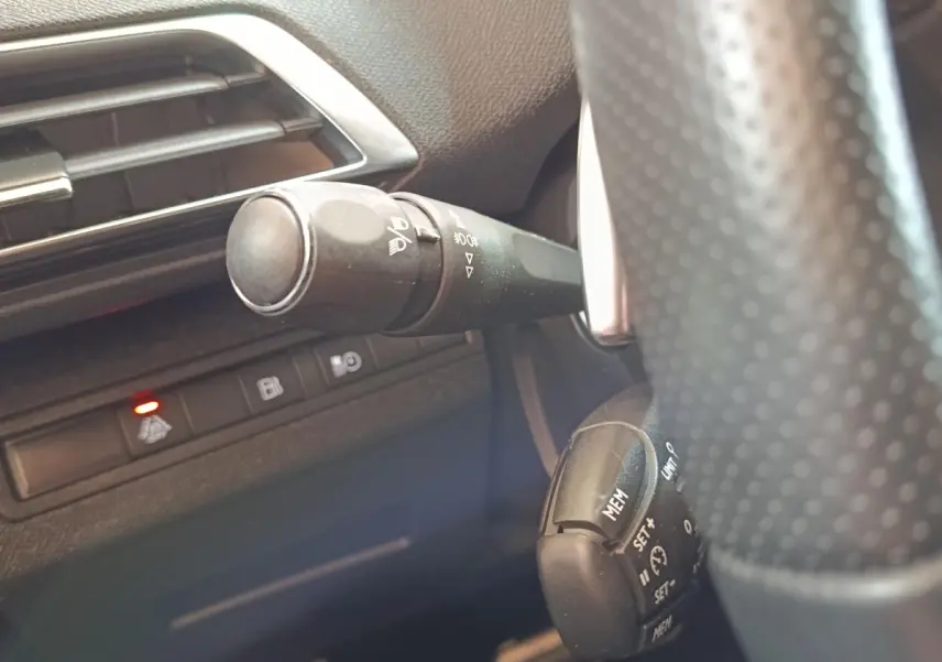 Détail intérieur du Peugeot 3008 bleu 2020 montrant la commande des phares et le régulateur de vitesse près du volant.