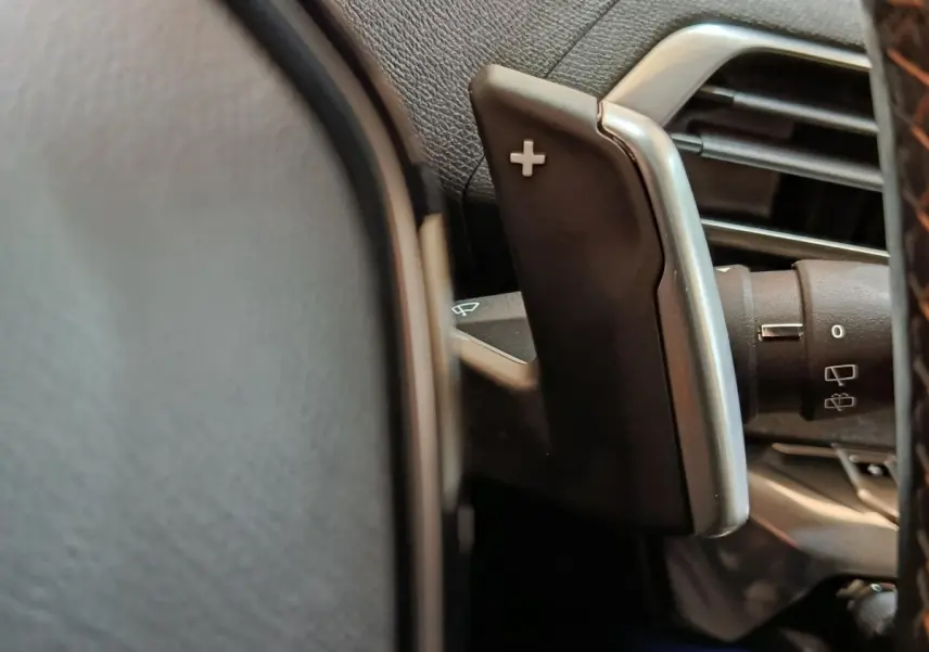 Gros plan sur la palette de changement de vitesse + au volant cuir du Peugeot 3008 bleu hybride rechargeable.