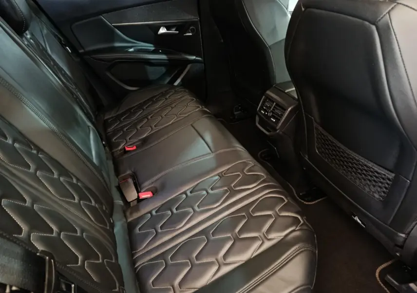 Vue intérieure arrière côté gauche du Peugeot 3008 1.6 Hybrid 225 GT Pack, sièges en cuir noir avec surpiqûres.