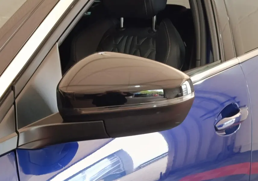 Rétroviseur noir en gros plan côté gauche sur Peugeot 3008 bleu hybride rechargeable, siège avant en cuir visible.