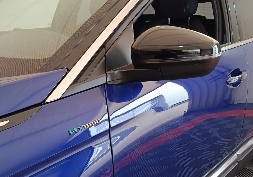 Détail du rétroviseur noir et logo HYBRID sur la porte côté gauche d’un Peugeot 3008 bleu.