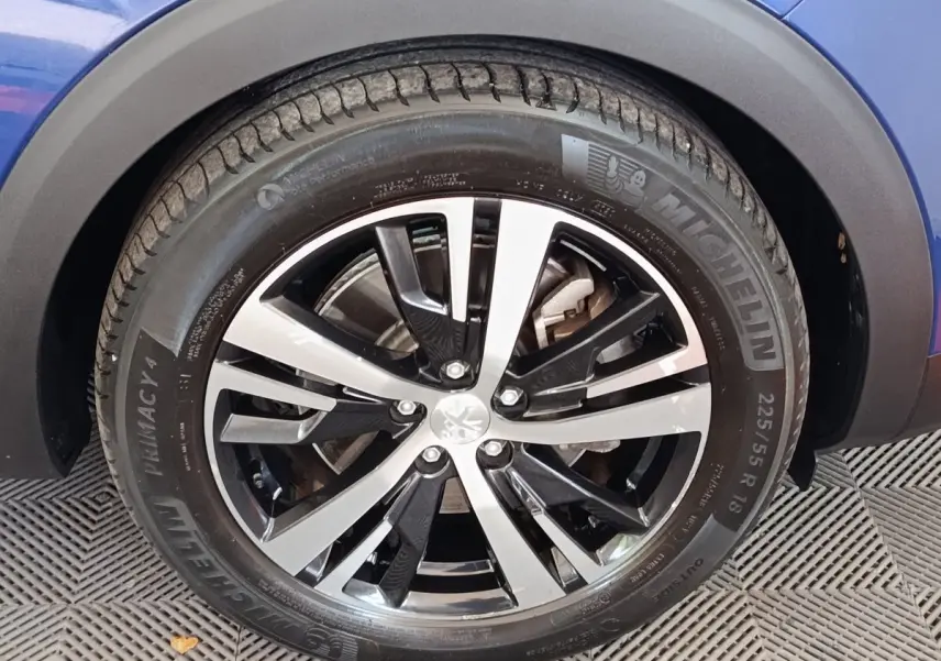 Gros plan sur la roue avant gauche du Peugeot 3008 bleu, avec jante alliage bicolore et pneu Michelin.