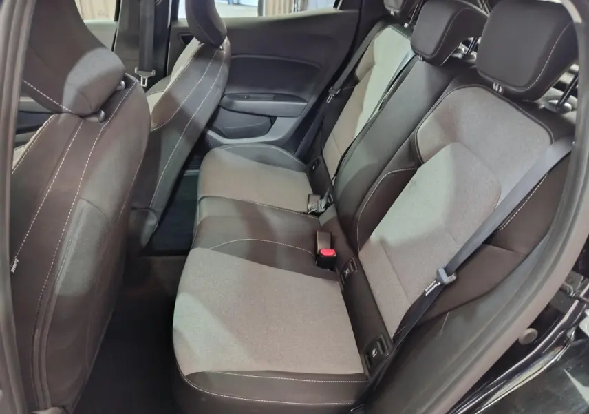 Vue côté droit sur l'intérieur arrière de la Renault Clio noire, montrant la banquette bi-ton gris et noir avec ceintures de sécurité.