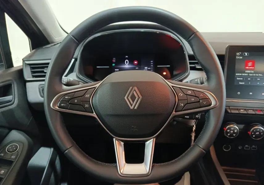 Vue intérieure centrée sur le volant cuir noir multifonctions de la Renault Clio 2025 avec tableau de bord numérique et écran tactile.