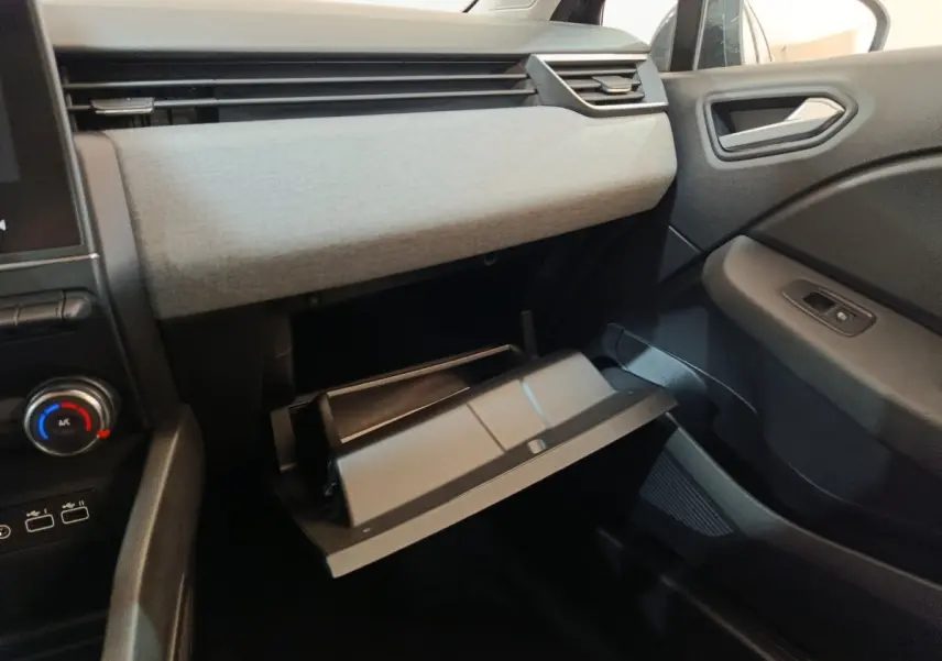 Intérieur côté passager de la Renault Clio noir 2025, avec boîte à gants ouverte et tableau de bord gris clair.
