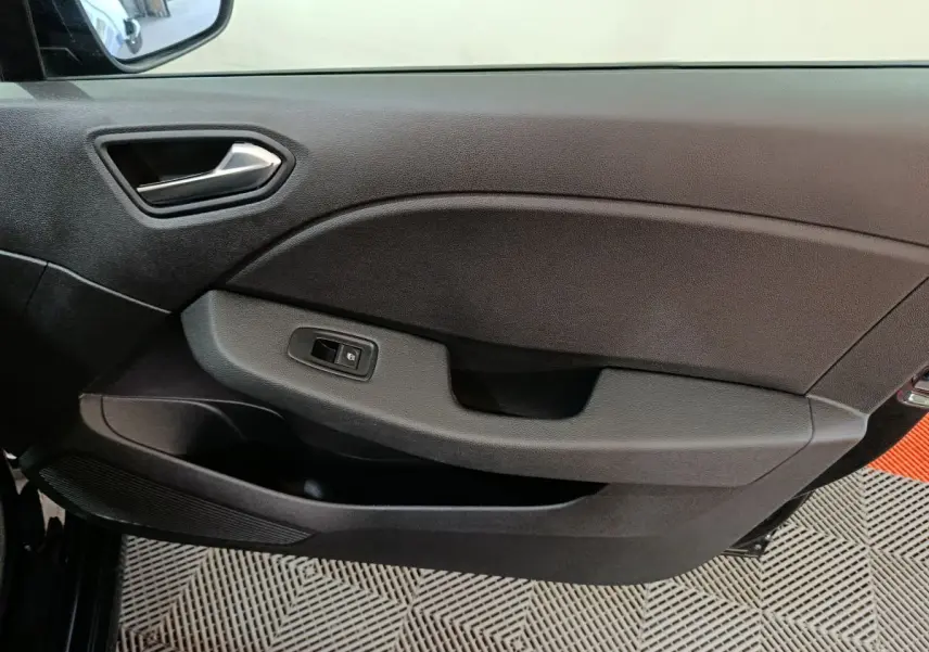 Vue rapprochée de la porte intérieure côté conducteur de la Renault Clio noire, avec commande de vitre électrique.