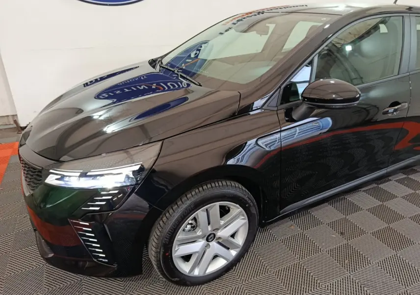 Vue 3/4 avant droit d'une Renault Clio noire 2025 avec phares LED allumés et jantes alliage argentées.