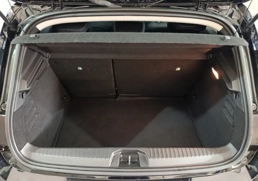 Coffre ouvert vu de l'arrière d'une Renault Clio noire 2025, montrant l'espace de chargement vide et l'éclairage intérieur.
