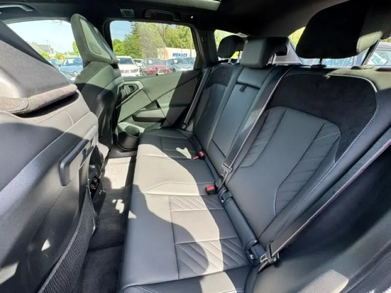 Vue intérieure côté droit des sièges arrière en Alcantara noir du BMW X3 xDrive20 2024 avec ceintures et appuie-têtes visibles.