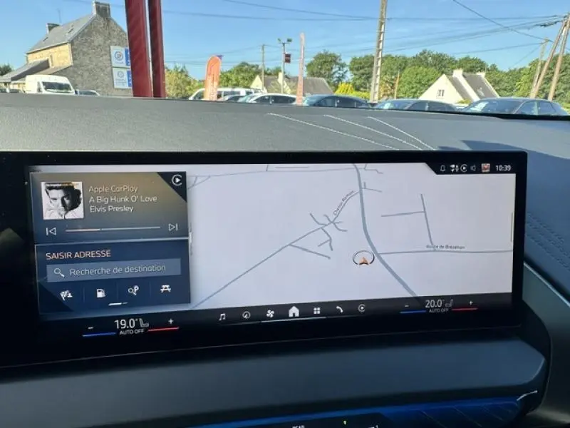 Vue intérieure du tableau de bord du BMW X3 xDrive20 2024 avec écran tactile large affichant navigation et musique, finition Alcantara noire.