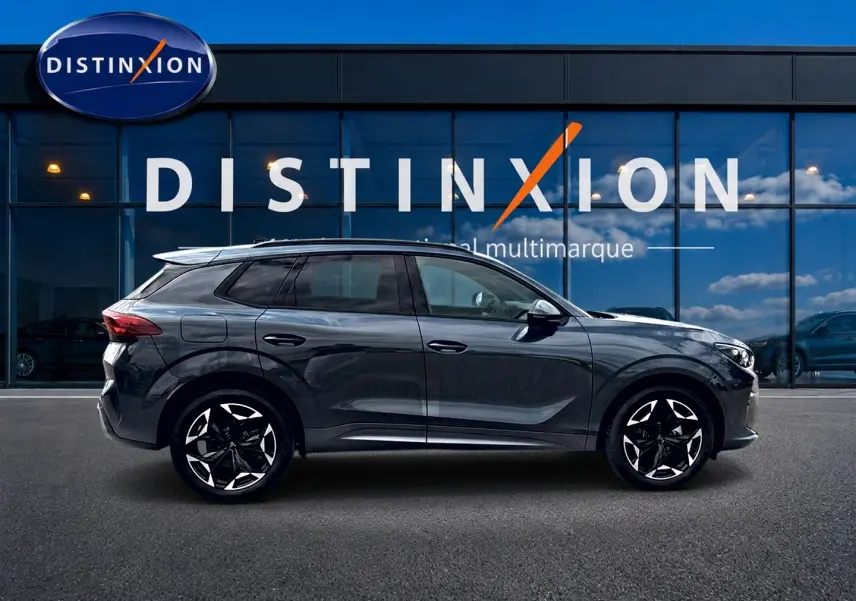 Vue latérale droite du SUV CUPRA TERRAMAR gris Timanfaya avec jantes noires et détails modernes devant une vitrine Distinxion.