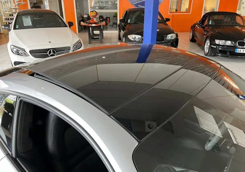 Vue plongeante sur le toit panoramique noir d'une Porsche 911 Carrera S argent GT en concession.