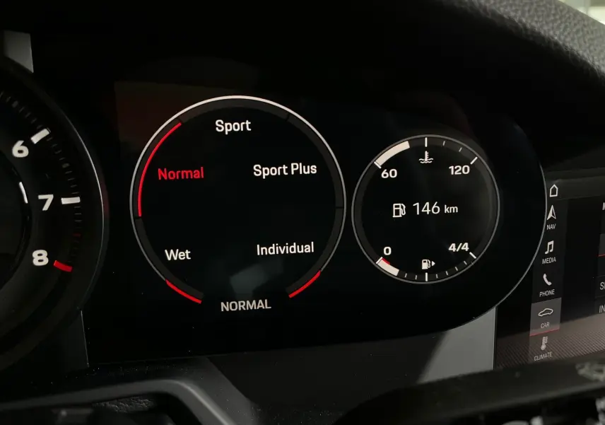 Tableau de bord numérique de Porsche 911 (992) affichant les modes de conduite et l'autonomie restante à 146 km.