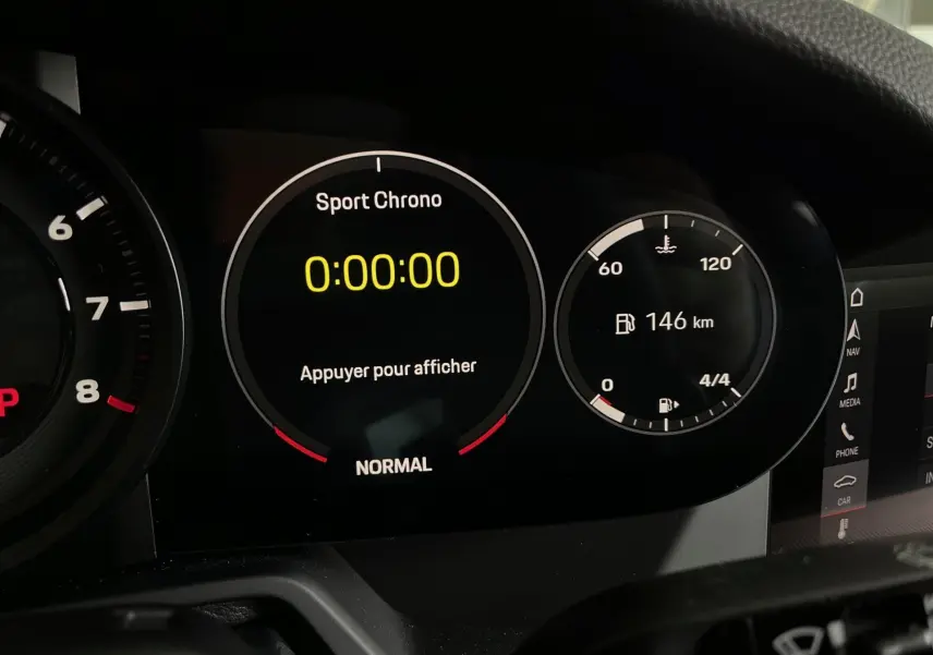 Gros plan sur le tableau de bord numérique de la Porsche 911 Carrera S 2019 avec affichage Sport Chrono et autonomie de 146 km.
