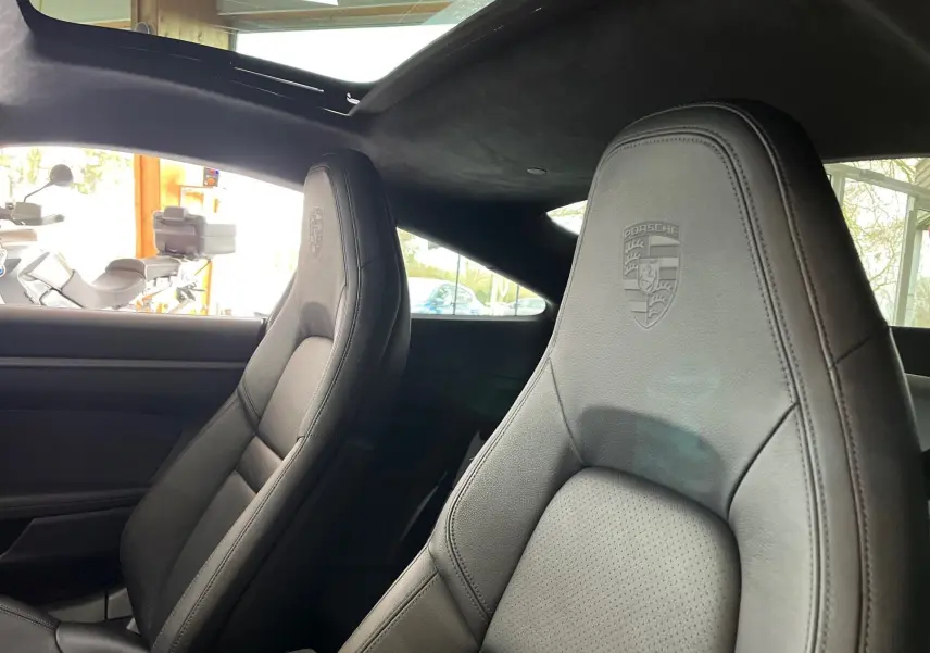 Gros plan sur les sièges avant en cuir noir embossés du logo Porsche dans l'habitacle d'une 911 Carrera S 2019.