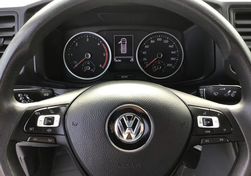 Vue rapprochée du volant multifonction noir avec logo Volkswagen et tableau de bord numérique du Crafter Fourgon blanc 2021.