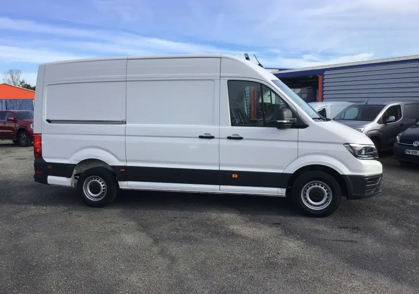 Vue de profil côté droit d'un fourgon Volkswagen Crafter blanc L3H3 avec bande noire basse et toit surélevé.
