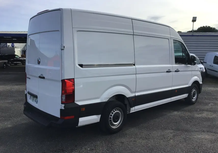 Vue 3/4 arrière droite d'un Volkswagen Crafter blanc L3H3, fourgon utilitaire avec porte latérale coulissante fermée.
