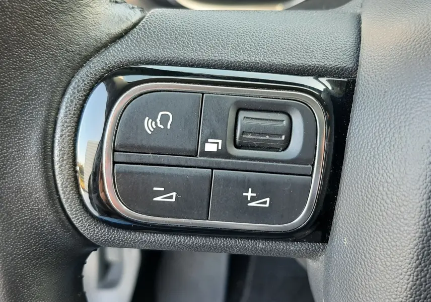 Gros plan sur les commandes de volume et de fonction vocale sur le volant noir du Citroën C5 Aircross gris 2021.