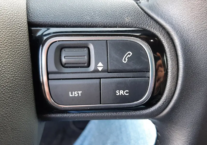 Gros plan sur les commandes gauche du volant noir du Citroën C5 Aircross gris, boutons LIST, SRC et téléphone visibles.