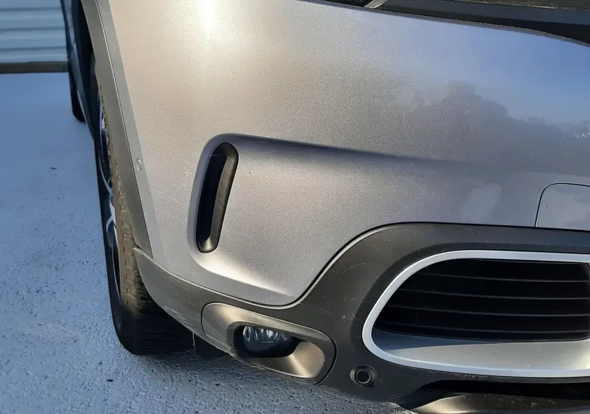 Gros plan sur l'avant gauche gris Artense du Citroën C5 Aircross 2021, mettant en valeur le phare et le pare-chocs.